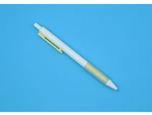 Detailweergave van een witte intrekbare balpen met een gele matte grip op een blauwe basis