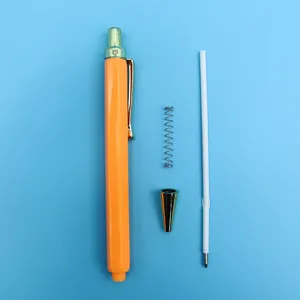 Orange retractable ballpoint pen disassembled with spring and refill on blue background