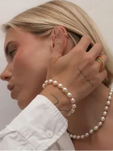 Primer plano de un conjunto de collar y pulsera de perlas neón usado por una bella modelo