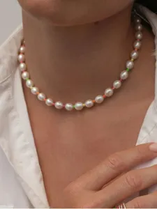 Primer plano de un collar de perlas neón con cuentas de colores en una modelo con camisa blanca.