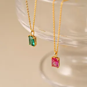 Détail de colliers en or élégants avec pendentifs en pierres précieuses vertes et roses.