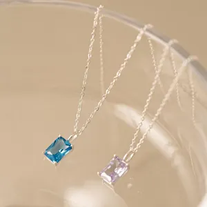 Gros plan de colliers en argent avec pendentifs rectangulaires en pierres bleue et violette