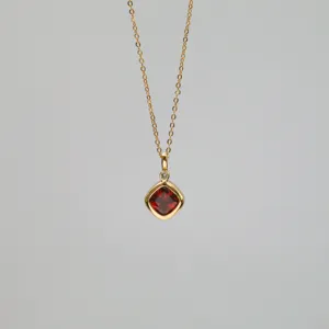 Detailed view of a square red garnet pendant on a dainty 18k gold plated necklace
