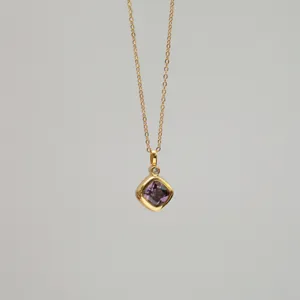 Close-up of golden necklace with a square purple zirconia pendant and small diamond accent