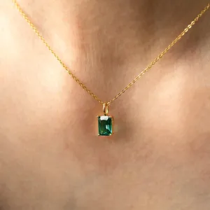 Gros plan d'un collier en or avec un pendentif rectangulaire en émeraude verte chic.