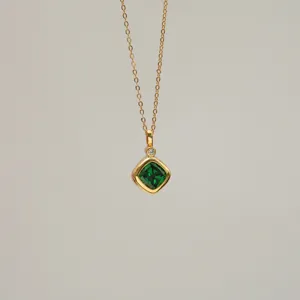 Macro detail of square emerald green zircon pendant on 18K gold plated copper chain