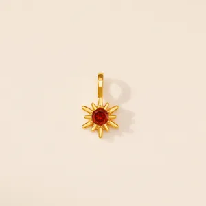 Gros plan détaillé d'un pendentif étoile solaire doré serti d'une pierre rouge.