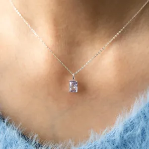 Gros plan d'un pendentif en cristal violet carré sur une chaîne en argent au cou