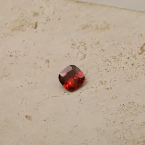 Macro view of a faceted red cushion-cut cubic zirconia gemstone birthstone charm