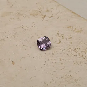 Detailed close-up of a brilliant cushion-cut purple zircon gemstone showing fine facets