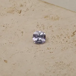 Macro detail of a faceted cushion cut lavender zircon birthstone on textured surface