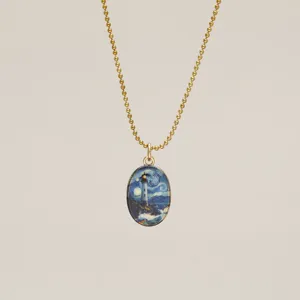 Macro view of luminous Starry Night lighthouse pendant on gold ball chain