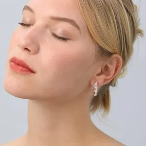 Close-up of elegant S925 sterling silver twisted hoop earrings with micro-set zircon on model.