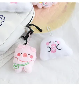 Close-up of cute pink pig and white candy plush pendants attached to a white bag