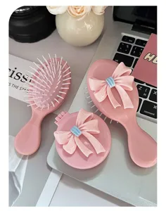 Cute pink hairbrush and mirror set with 3D bow decoration on a white laptop desk