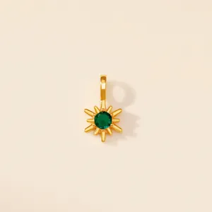 Vue détaillée d'un pendentif étoile à huit branches en acier titane doré avec gemme verte.