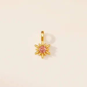 Gros plan d'un pendentif étoile à huit branches plaqué or avec une pierre de zircon rose.