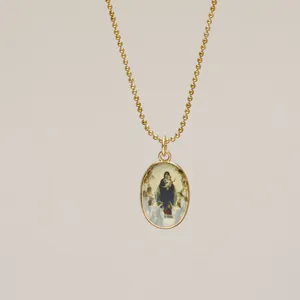 Detailed view of an oval gold pendant necklace with a vintage religious painting