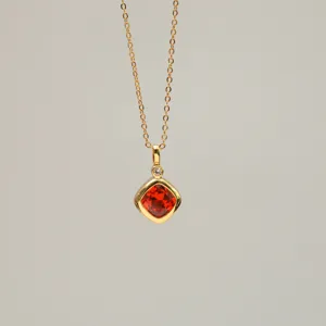 Detailed macro view of an 18K gold-plated necklace featuring a radiant orange zircon