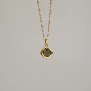 Macro view of a gold-plated necklace with an olive green square zircon pendant