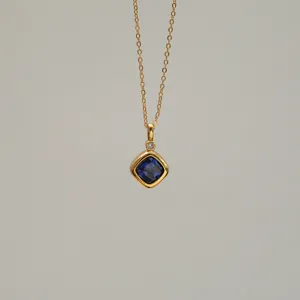Detailed macro view of gold-plated necklace with a square sapphire blue zircon pendant.