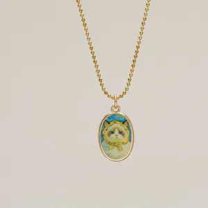 Close-up detail of a vintage gold pendant necklace with a cute hand-painted cat motif