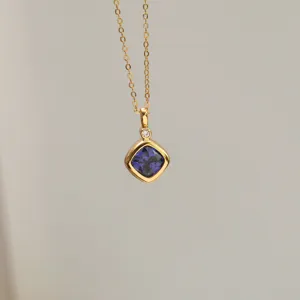 Close-up of 18K gold plated necklace featuring square blue zircon birthstone pendant