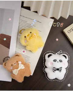 Primer plano de lindos llaveros de peluche con forma de pollito, oso y panda en un escritorio