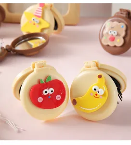 Close-up of cute cartoon folding mirror hairbrushes with apple and banana designs
