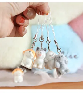 Detail showing four miniature flocked puppy dog keychain charms held in a human hand