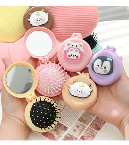Close-up of portable cartoon mini pocket hair brushes with mirrors held in hands
