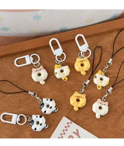 Close-up of various cute cat-shaped donut keychains and phone charms on a wooden tray