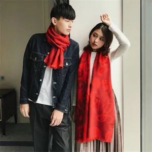 A stylish couple wearing elegant red festive scarves with traditional circular patterns