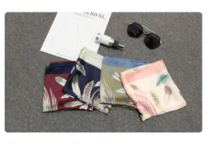 Detailed view of square silk-like scarves featuring elegant feather patterns in multiple colors