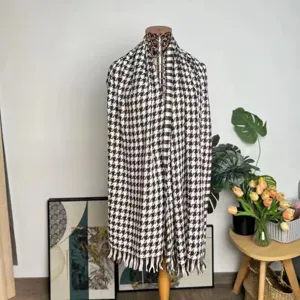 Detailed texture view of a black and white houndstooth scarf with elegant fringe.