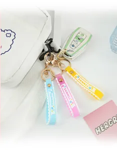 Close-up of three colorful silicone wristlet keychains with gold clasps on a white bag