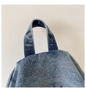 Detailopname van het handvat aan de bovenkant van de denim rugzak, casual stijl.