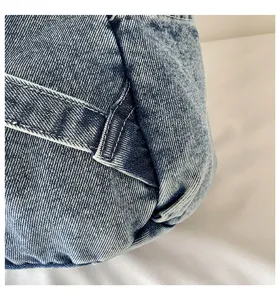 Close-up detailweergave van vintage gewassen denim stof met stevige witte stiksels.