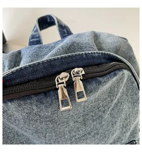 Detailopname van ritssluiting en handvat van vintage denim rugzak met sterke stof.