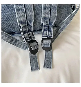 Close-up van de banden van de vintage gewassen denim rugzak en verstelbare plastic gespen.