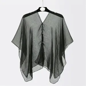Detail view of black sheer chiffon shawl with pearl buttons and tassels