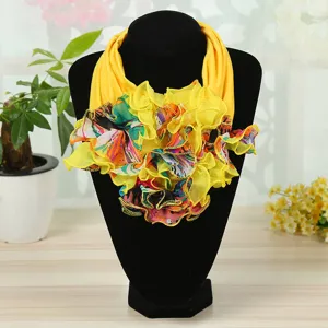 Detail view of a yellow silk neck warmer featuring vibrant ruffled floral patterns