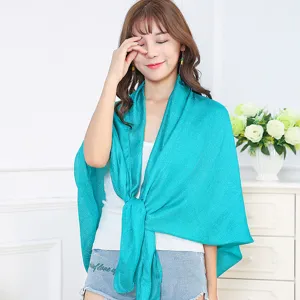 Elegant model styling a vibrant turquoise linen shawl for beach and sun protection