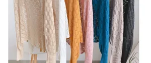 Detailed view of women's honeycomb pattern knit shawls in various vibrant colors on a rack.