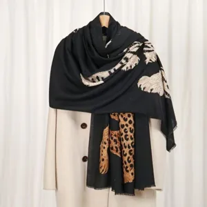 Detail view of a black faux cashmere scarf with leopard and feather prints.