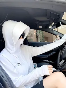 Close-up detail of a white sun protection hoodie with face mask and thumb holes in a car