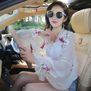 Detail of white embroidered sun protection shrug sleeves worn for driving in a car