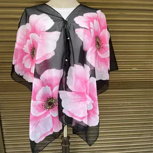 Detail des schwarzen Chiffon-Schals mit großen rosa Blumendrucken und Perlenknöpfen