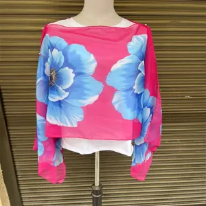 Detailansicht eines leuchtend rosa Chiffon-Schals mit Blumenmuster und Perlenakzenten.
