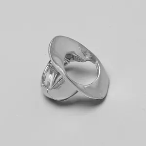 Detalle de anillo elástico ovalado plateado con textura metálica orgánica distorsionada